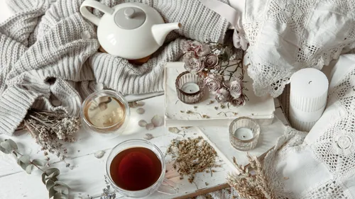 Teapot and cup on cozy, decorated table.