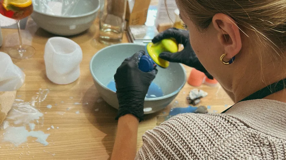 Person molding clay bowl at craft workshop.