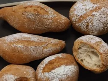 Brötchen liegen auf einem schwarzen Teller, einige angeschnitten.