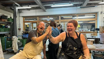 Two people high-fiving in a pottery studio.