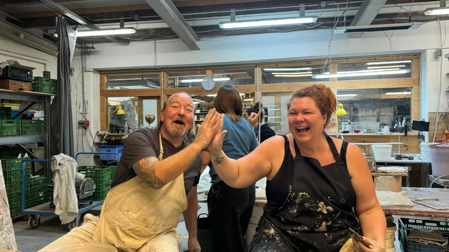 Two people high-fiving in a pottery studio.