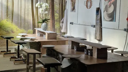 Pottery studio with stools and wooden tables.