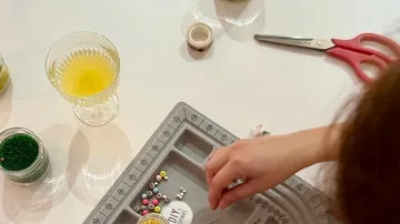 Person sortiert Perlen auf einem Tablett.
