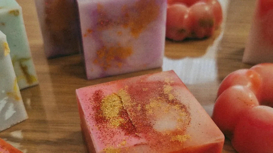 Colorful soaps and tomatoes on wooden surface.