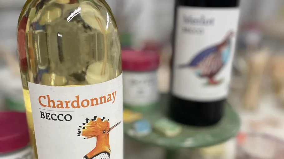 Two wine bottles with bird labels on a table.