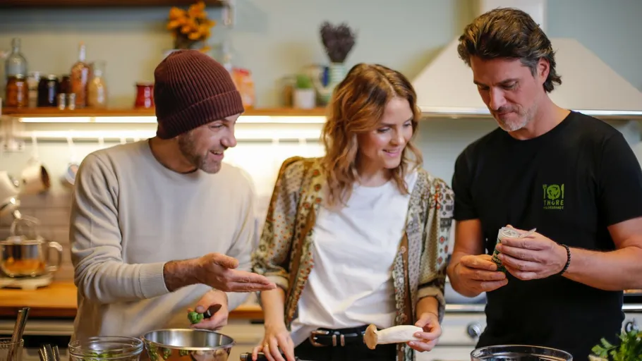 Three people preparing food in kitchen.