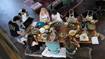 Gruppe kocht gemeinsam an großem Tisch.