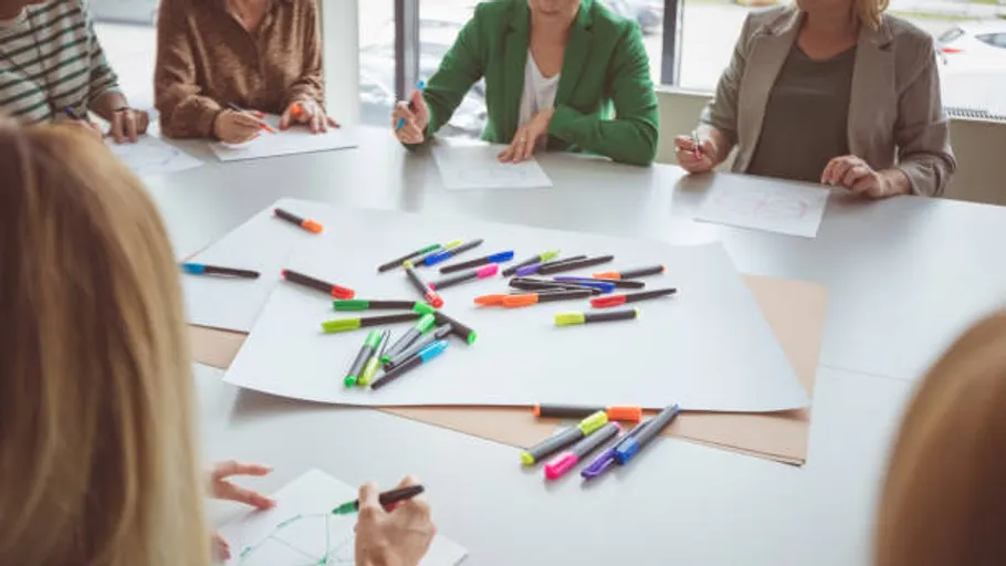 People drawing around a table with markers.