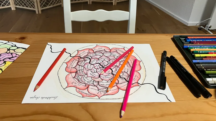 Buntstifte und Zeichnung auf Holztisch.