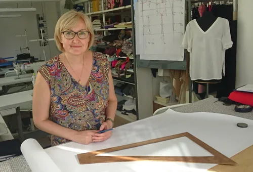 Frau steht mit Schnittpapier im Nähstudio.