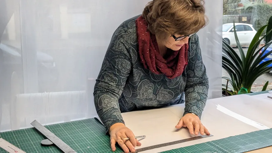 Woman measuring fabric on cutting table.