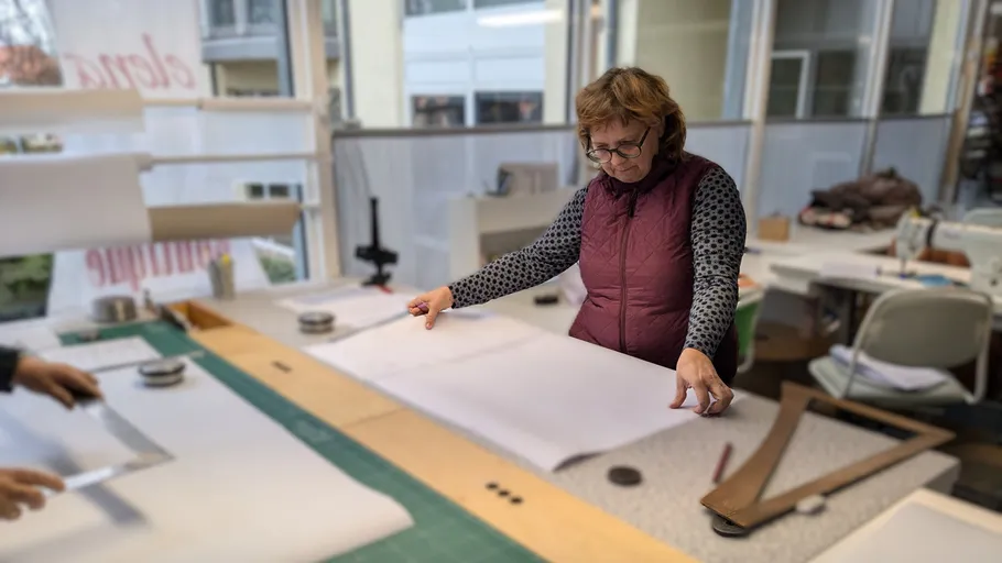 Woman cutting fabric on a workshop table.