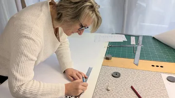 Frau misst und zeichnet am Designtisch.