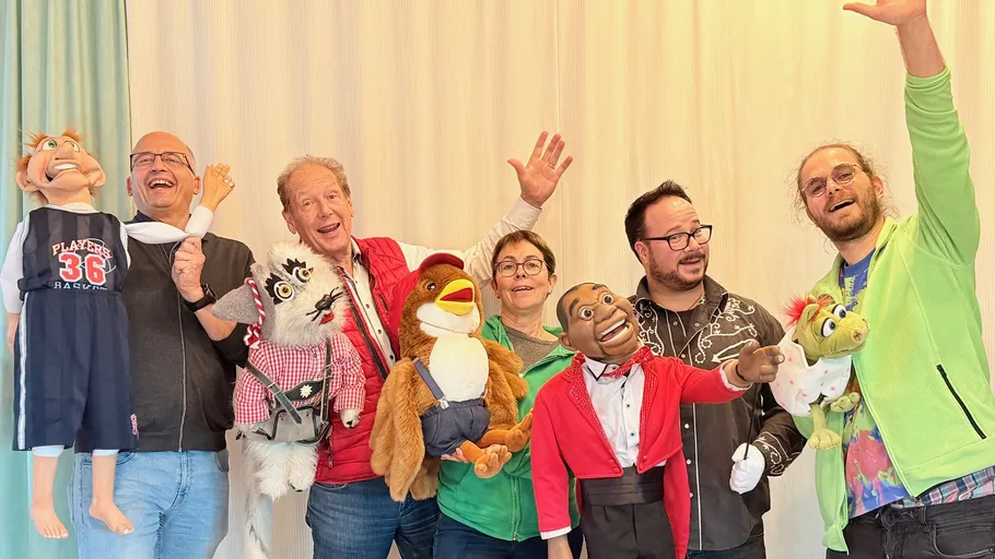 People holding puppets, smiling indoors.