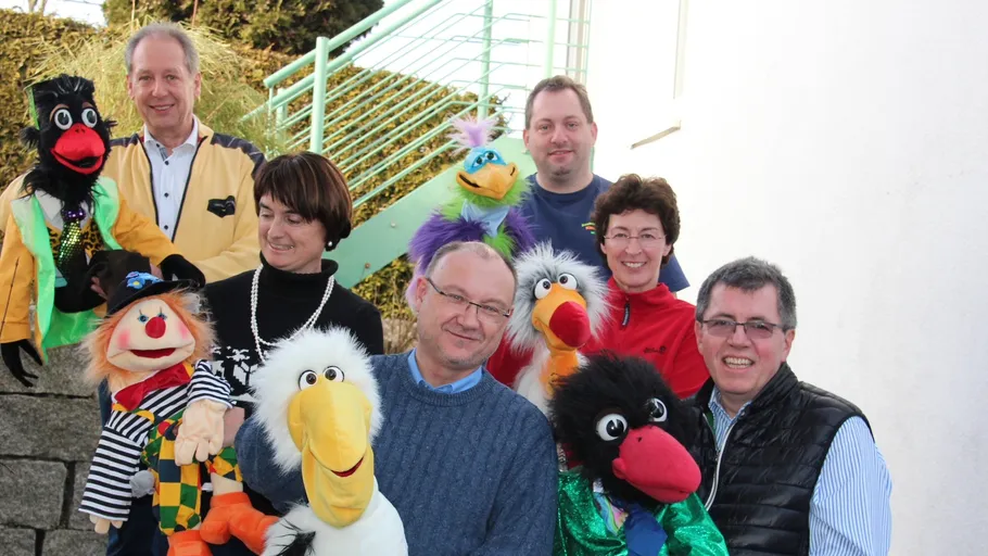 Gruppe hält bunte Puppen im Freien.