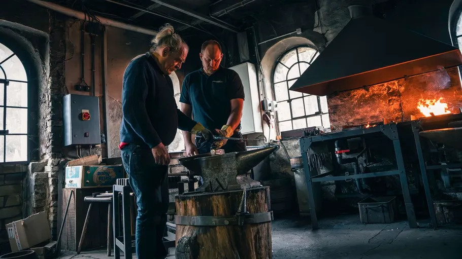 Two blacksmiths working in a forge.