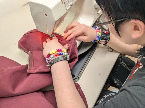 Person sewing fabric using a sewing machine.