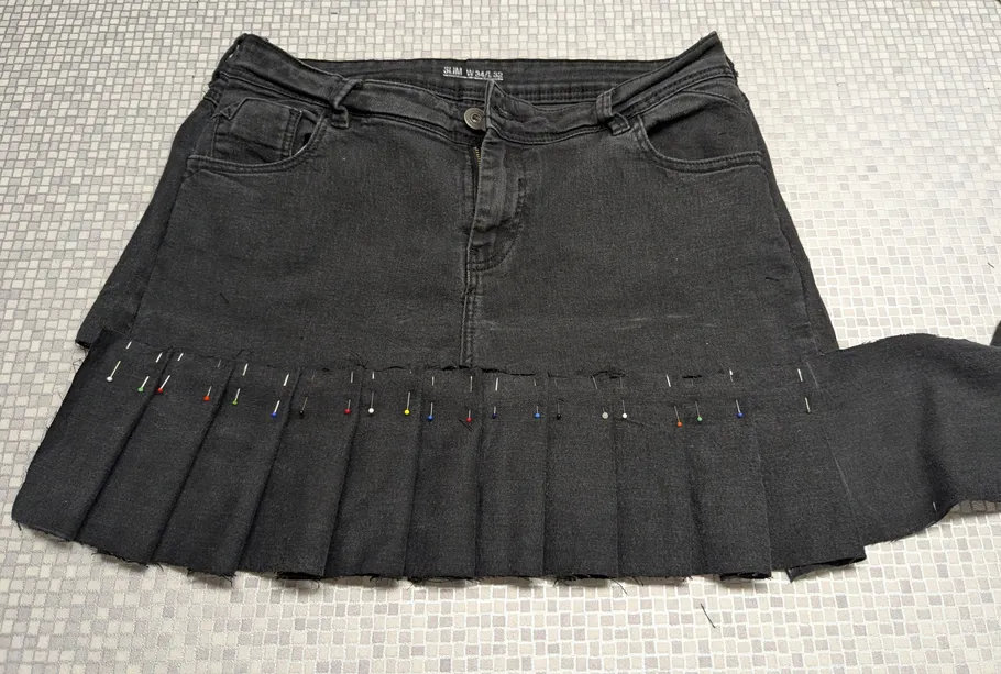 Schwarzer Rock mit Falten, zum Nähen festgesteckt.