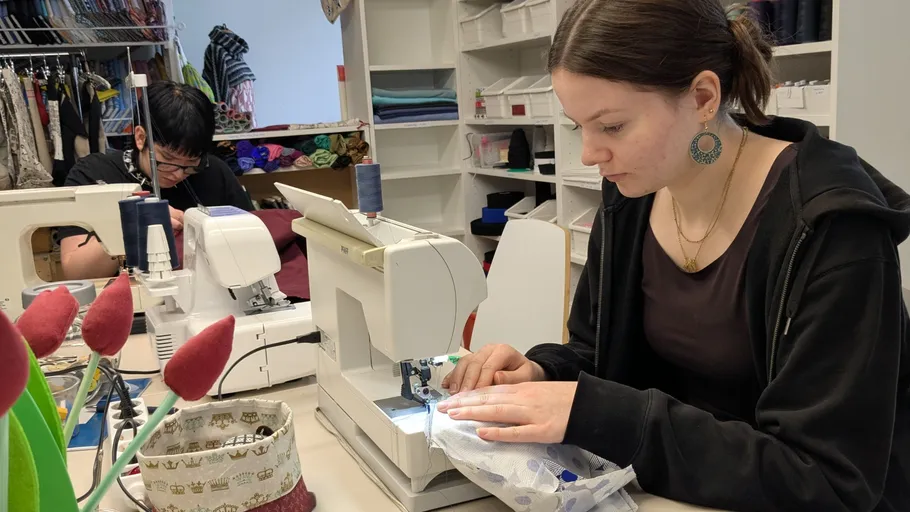 Two people sewing in a workshop.