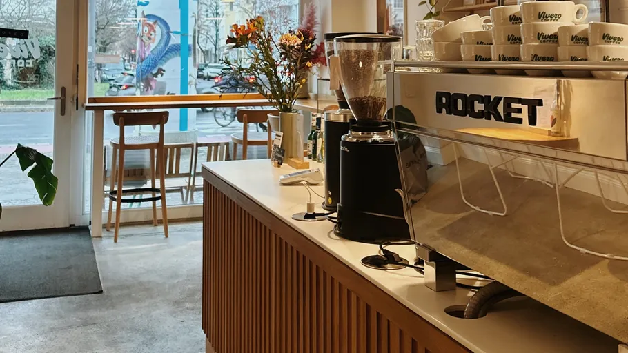 Café-Inneneinrichtung mit Kaffeemaschine und Holzhockern.