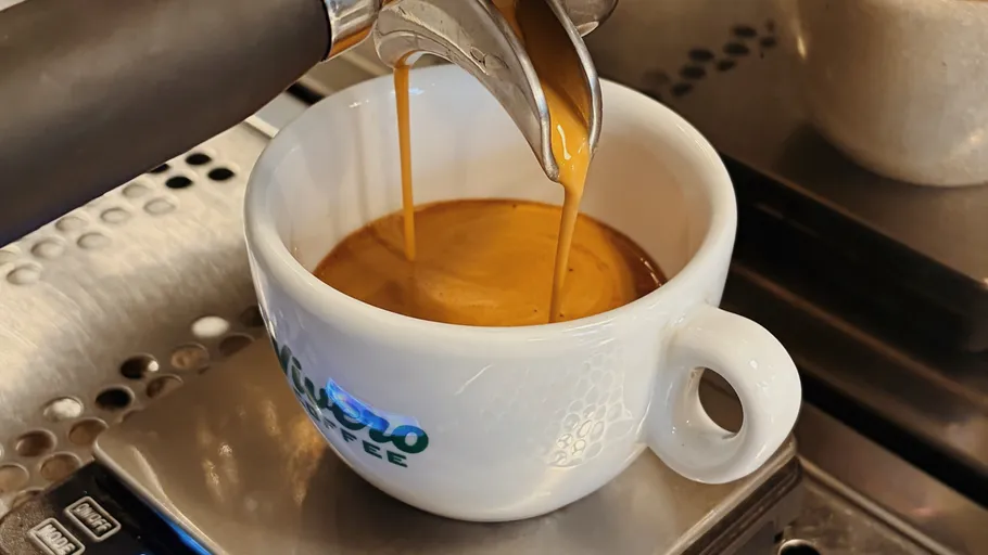 Espresso fließt in Tasse auf Maschine.