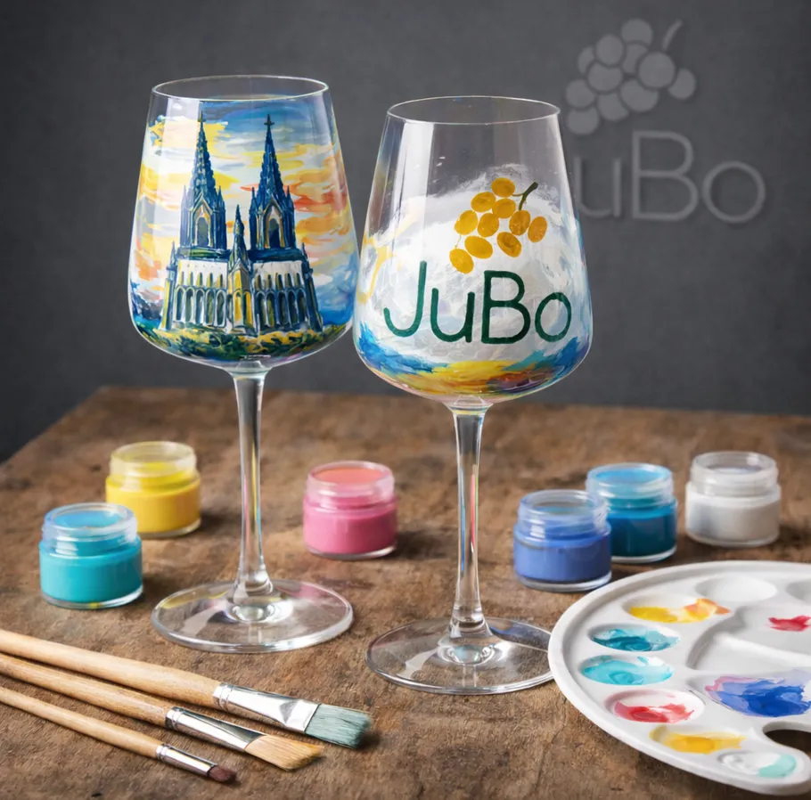 Bunt bemalte Weingläser mit Pinseln auf Tisch.