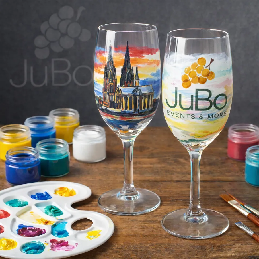 Painted wine glasses with art supplies on table.
