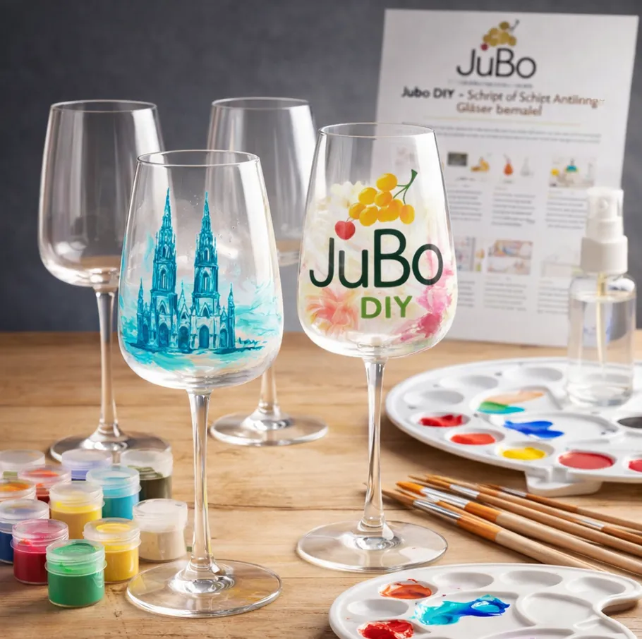 Painted wine glasses on wooden table with paints.