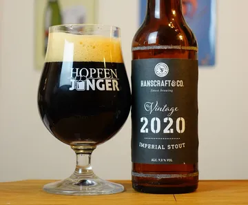 Ein Glas Bier steht neben einer Flasche Imperial Stout.