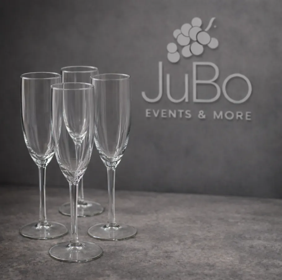 Four empty champagne flutes on gray background.
