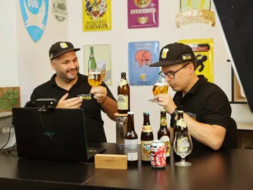 Zwei Männer verkosten Bier an einem Tisch mit Flaschen.