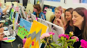 Women painting on canvases in art class.