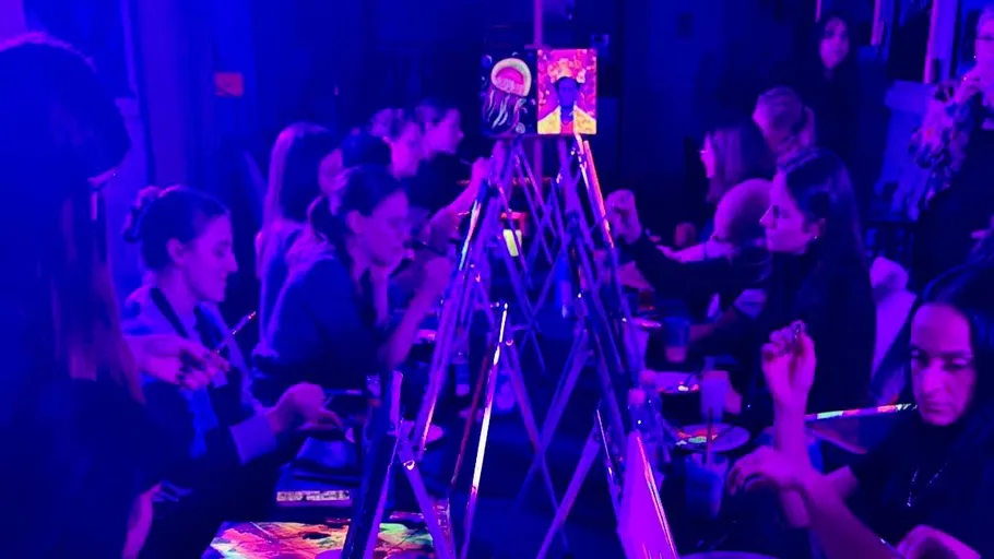 Group painting under colorful lights indoors.