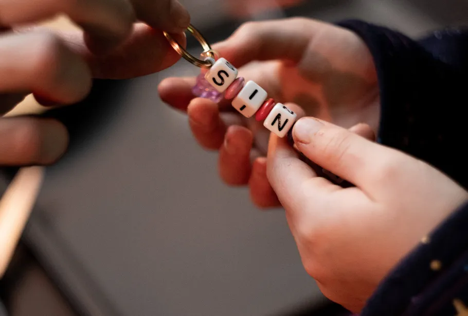 Hands holding keychain with 'SIN' beads.