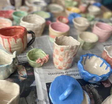 Colorful ceramic mugs on a newspaper surface.