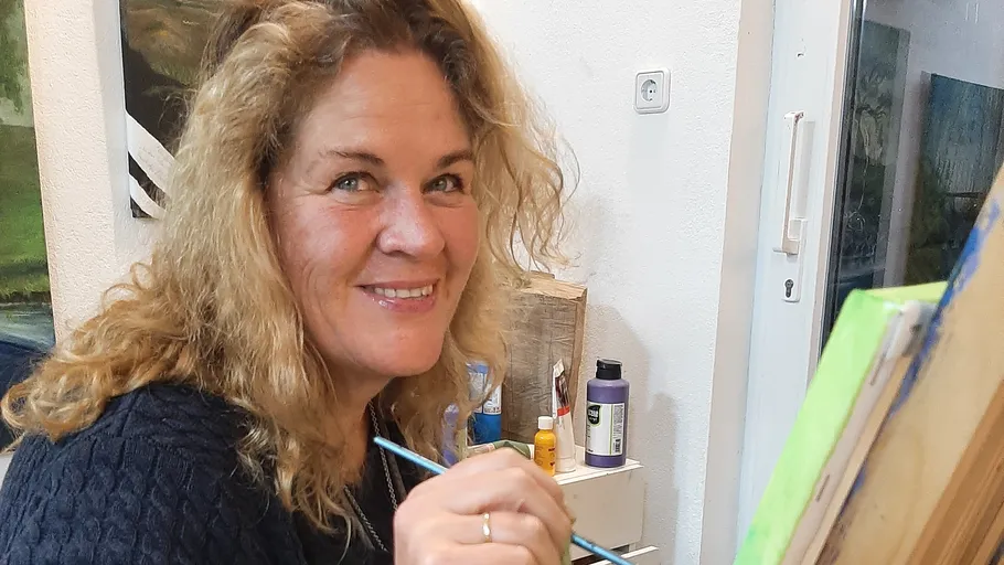 Smiling woman painting in art studio.