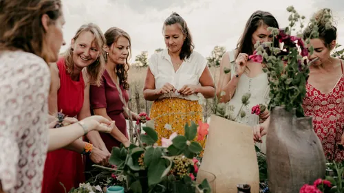 Gruppe von Frauen arrangiert Blumen im Freien.
