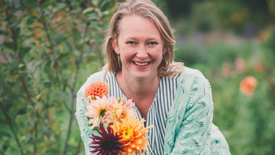Woman smiling, holding colorful flowers in garden.