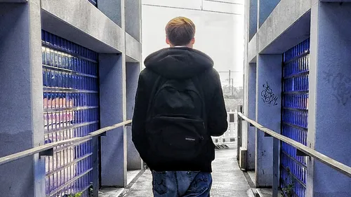 Person walking on urban pathway, wearing backpack.