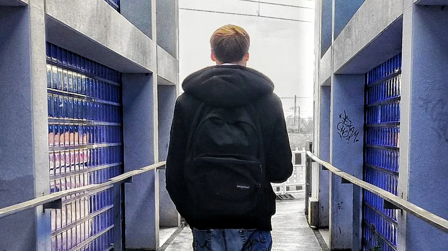 Person mit Rucksack geht zwischen Gebäuden.