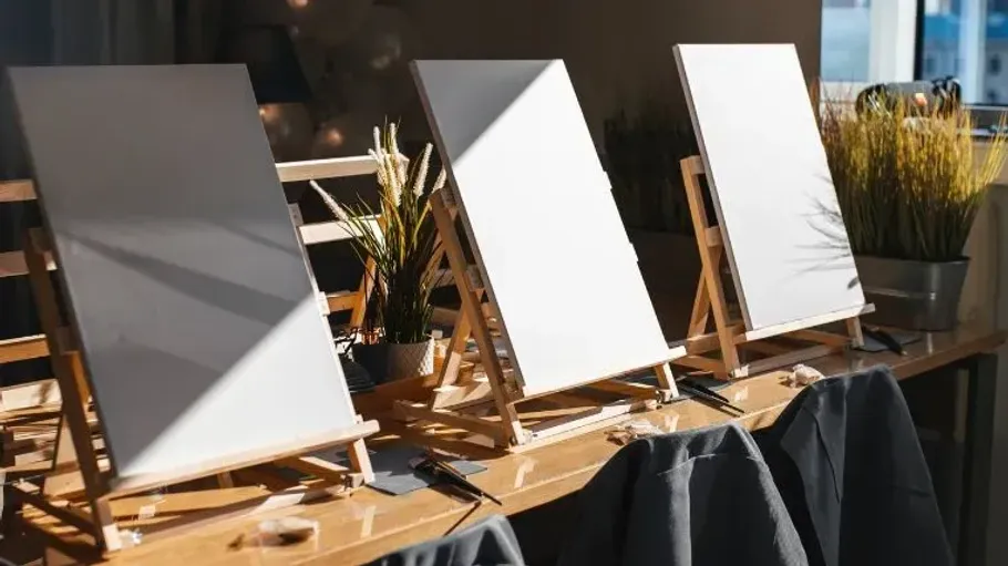 Three blank canvases on wooden easels indoors.