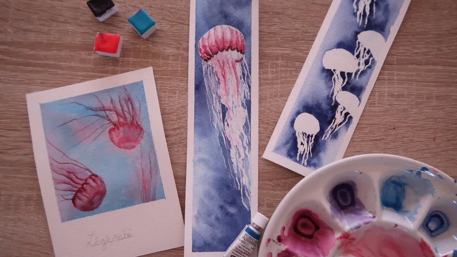 Jellyfish paintings on table with paints.
