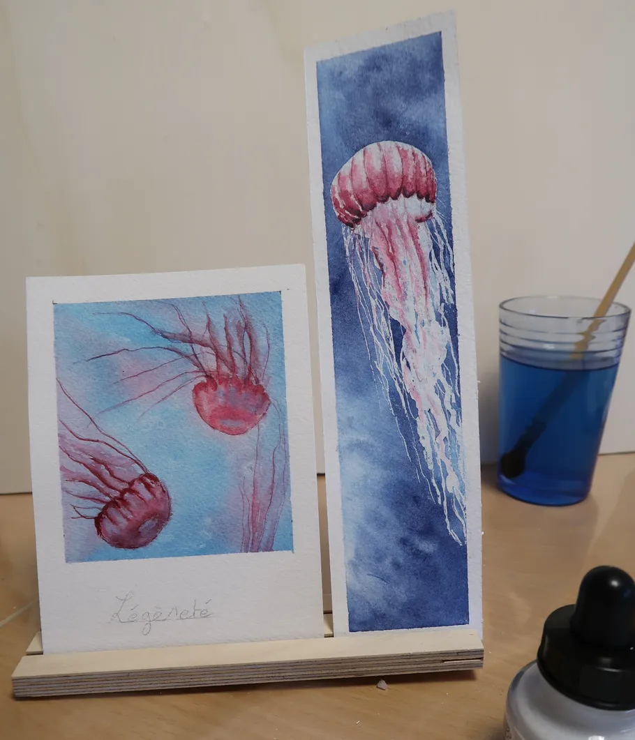 Zwei Quallen-Aquarelle auf einem Ständer.
