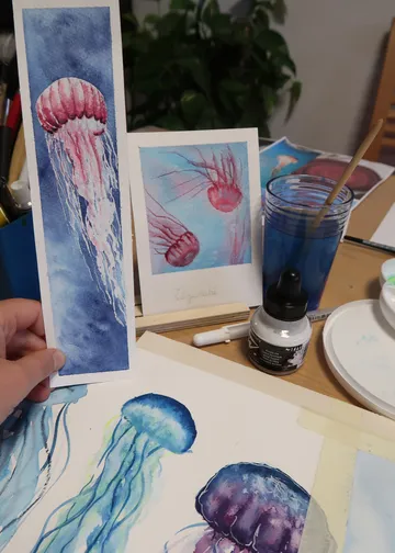 Hand hält Quallen-Aquarellbilder.