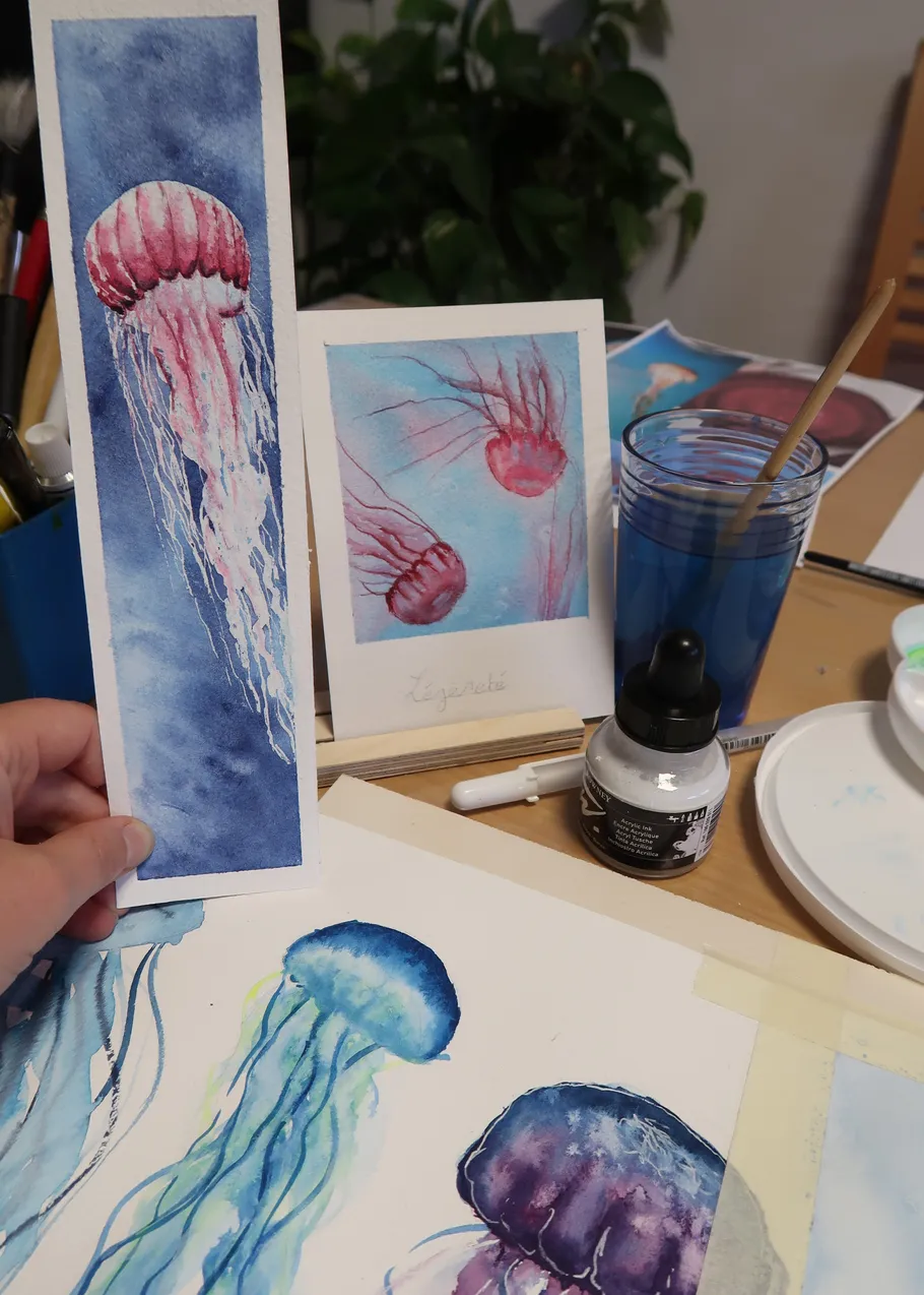 Hand hält Quallen-Aquarellbilder.