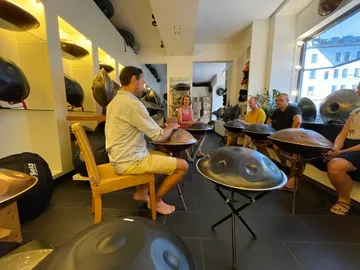 Group sitting together, playing handpan in a music store.