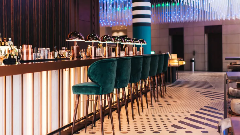 Modern bar with green chairs, stylish decor.