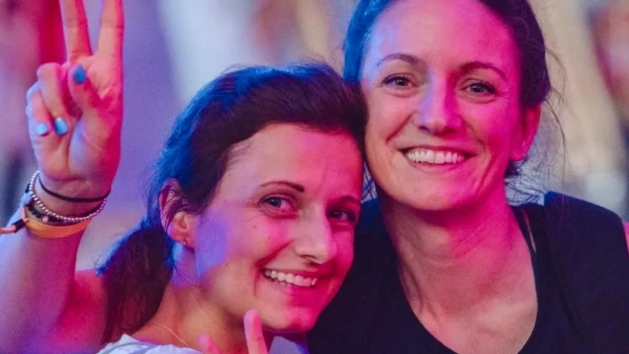 Two women smiling, one making a peace sign.