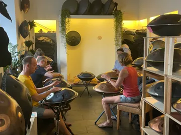 People play hand pans in a cozy, bright room.