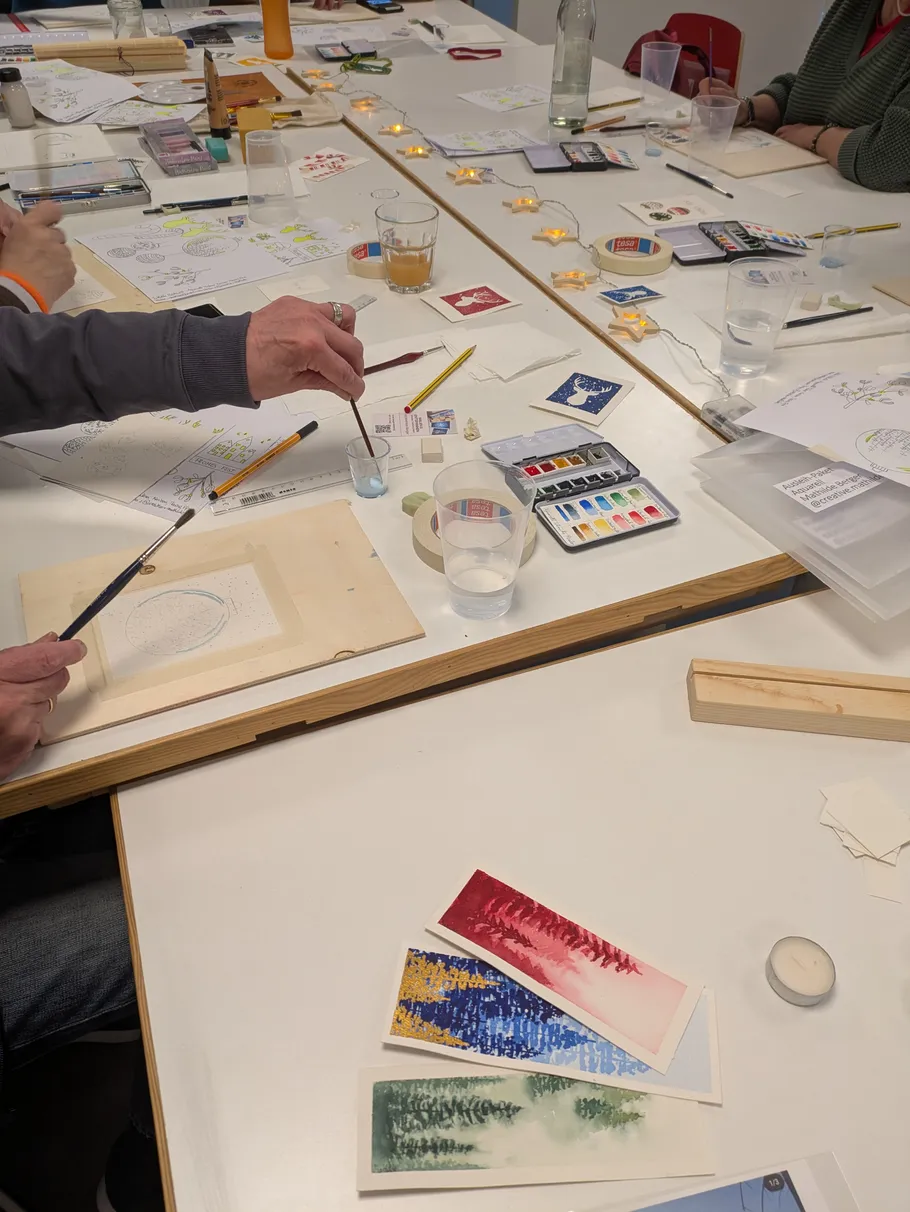 Menschen malen an einem Workshop-Tisch.